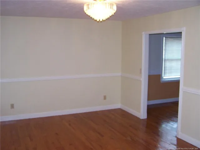 an empty room with wooden floor and window