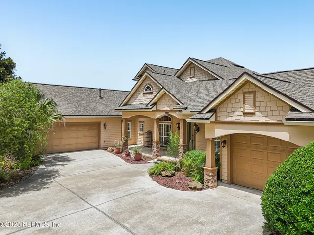 an aerial view of a house with yard and trees in the background