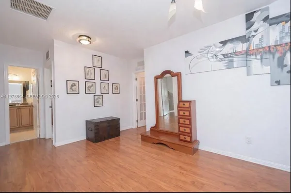 a view of a livingroom with wooden floor and kitchen space with a couch