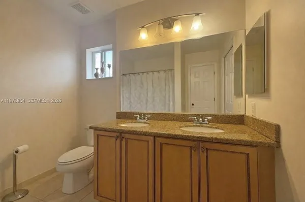 a bathroom with a granite countertop sink a toilet and a mirror