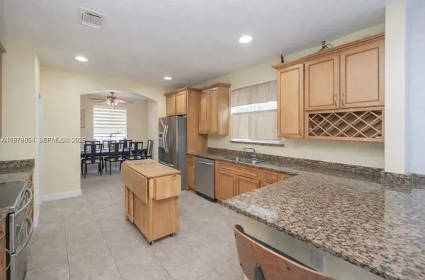 a large kitchen with kitchen island granite countertop a stove a sink a dining table and chairs