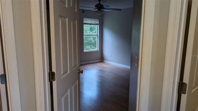 a view of an empty room with wooden floor and a window