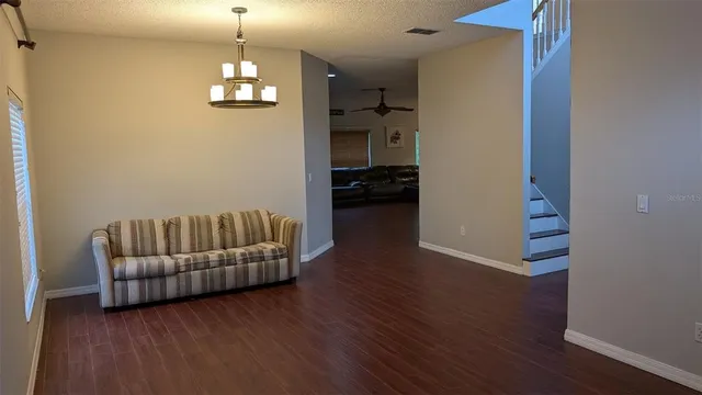 a living room with couches and a dining table with wooden floor
