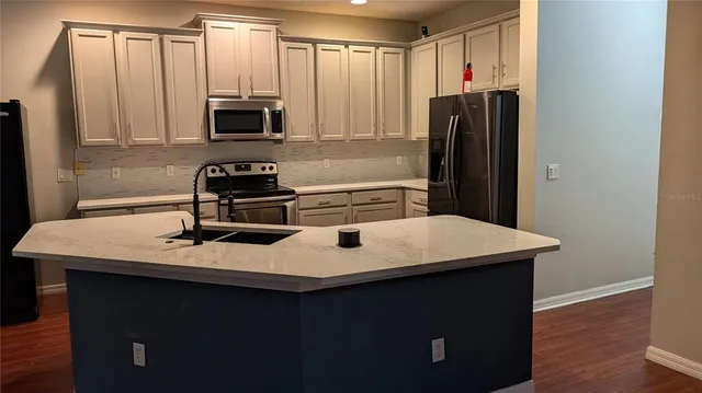 a kitchen with a sink a microwave a refrigerator and cabinets