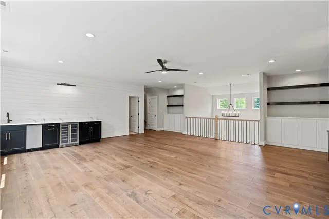 a view of an empty room with wooden floor and a kitchen