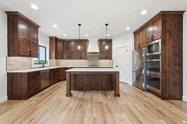 2970 North Mahogany Vly Road Logan, UT 84341 - Photo 8 of 39 Kitchen featuring dark wood finish cabinets, stainless steel appliances, a center island, pendant lighting, and light wood finished floors