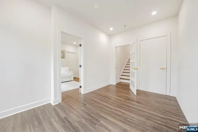 a view of an empty room with wooden floor and a ceiling fan