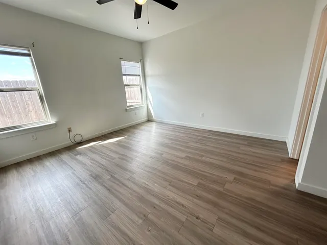 an empty room with wooden floor and windows