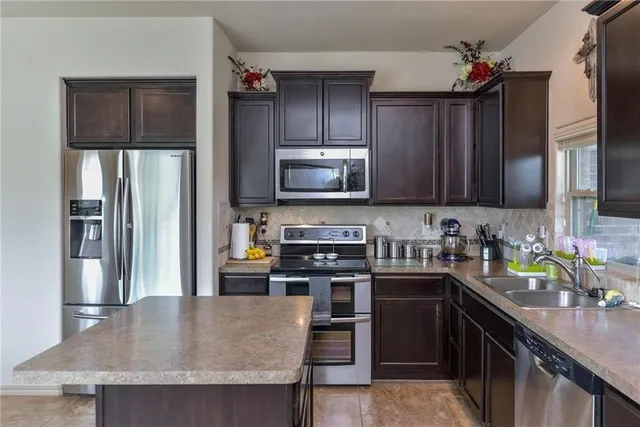 a kitchen with stainless steel appliances granite countertop a refrigerator a stove top oven a sink and dishwasher