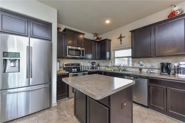 a kitchen with a sink a microwave a refrigerator and cabinets