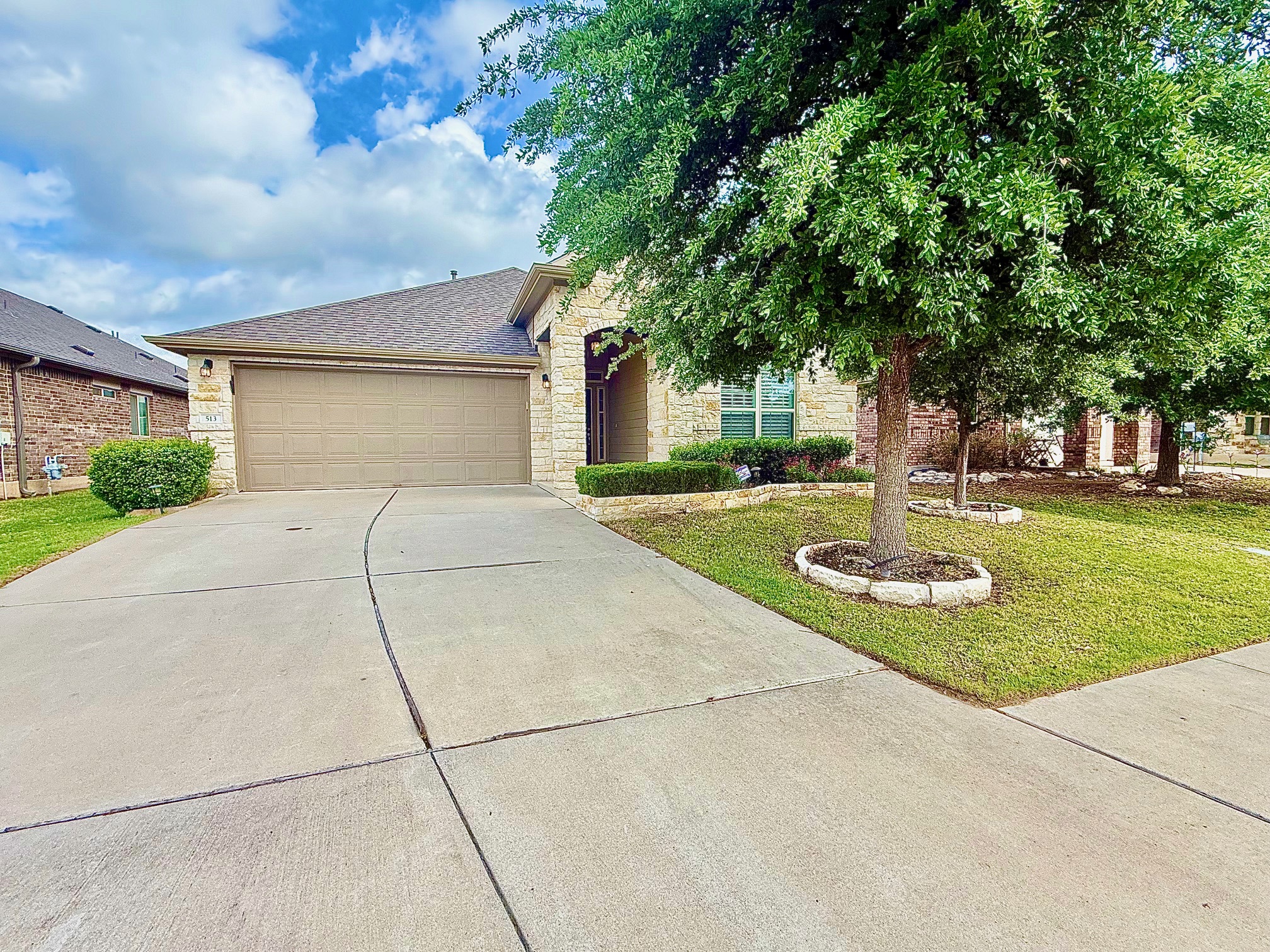 513 Longhorn Cavern Road Leander, TX 78641 - Photo 1 of 24 View of front of house featuring stone siding, a garage, driveway, a front lawn, and a shingled roof