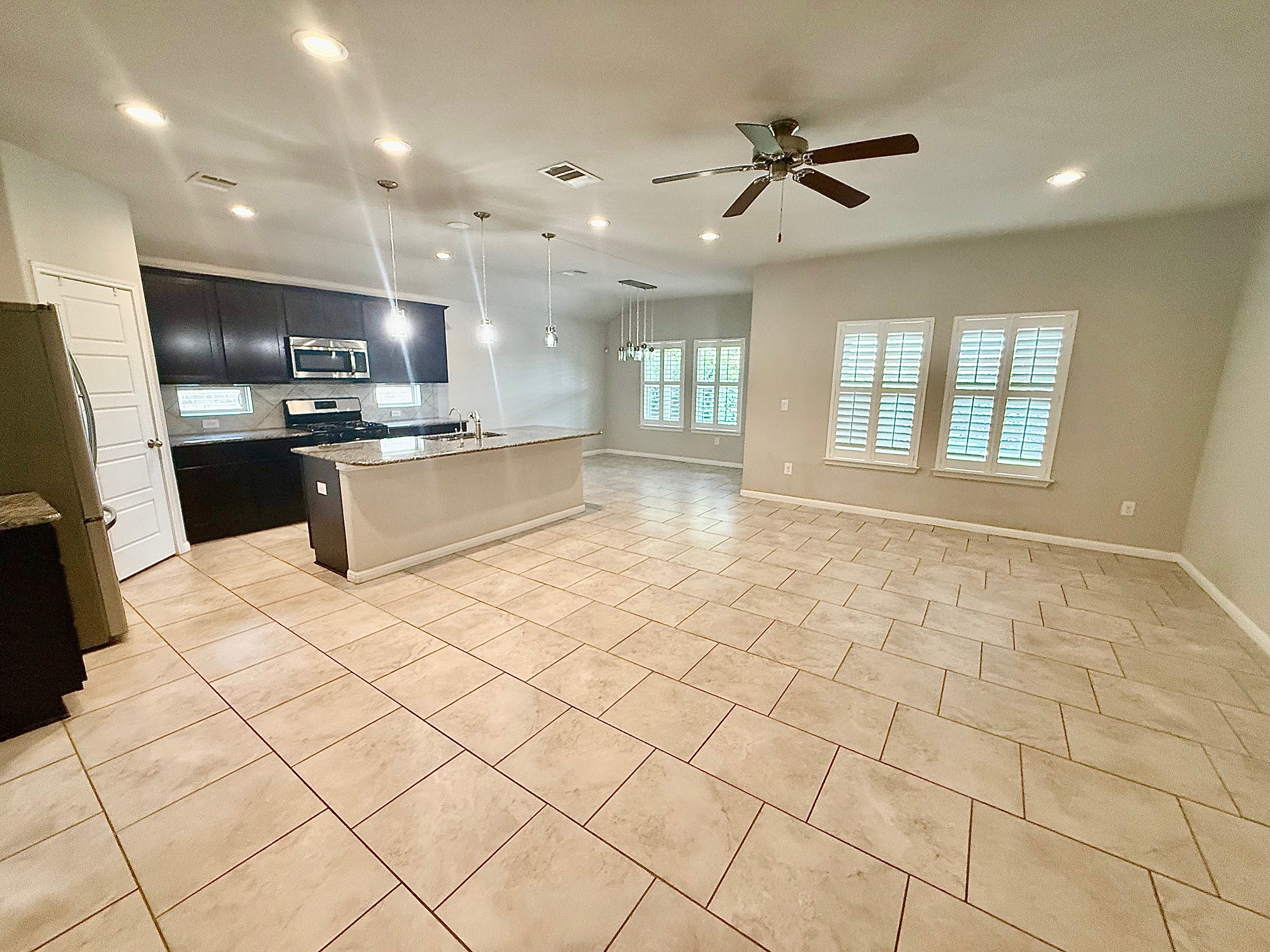 513 Longhorn Cavern Road Leander, TX 78641 - Photo 24 of 24 Kitchen with open floor plan, a kitchen island with sink, stainless steel appliances, light stone counters, and hanging light fixtures