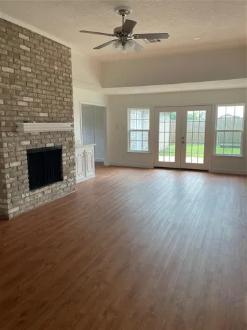 an empty room with windows fireplace and a kitchen view