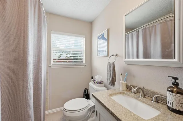 a bathroom with a granite countertop sink toilet and mirror