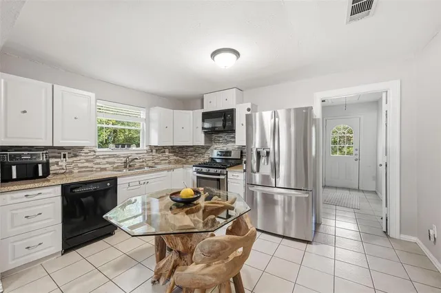 a kitchen with granite countertop a stove refrigerator and microwave