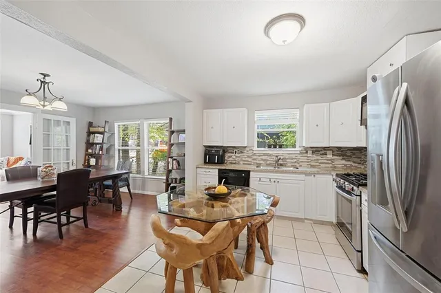 a kitchen with stainless steel appliances granite countertop a stove a refrigerator a kitchen island a dining table and chairs with wooden floor