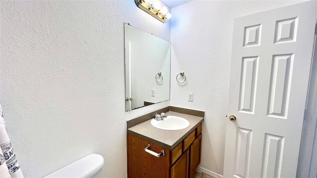 4503 Fortuna Street Fort Worth, TX 76119 - Photo 21 of 26 a bathroom with a sink a toilet and mirror