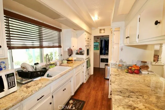 a large white kitchen with kitchen island a large window a sink and stainless steel appliances