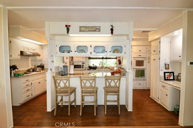 a kitchen with stainless steel appliances a dining table chairs and wooden floor