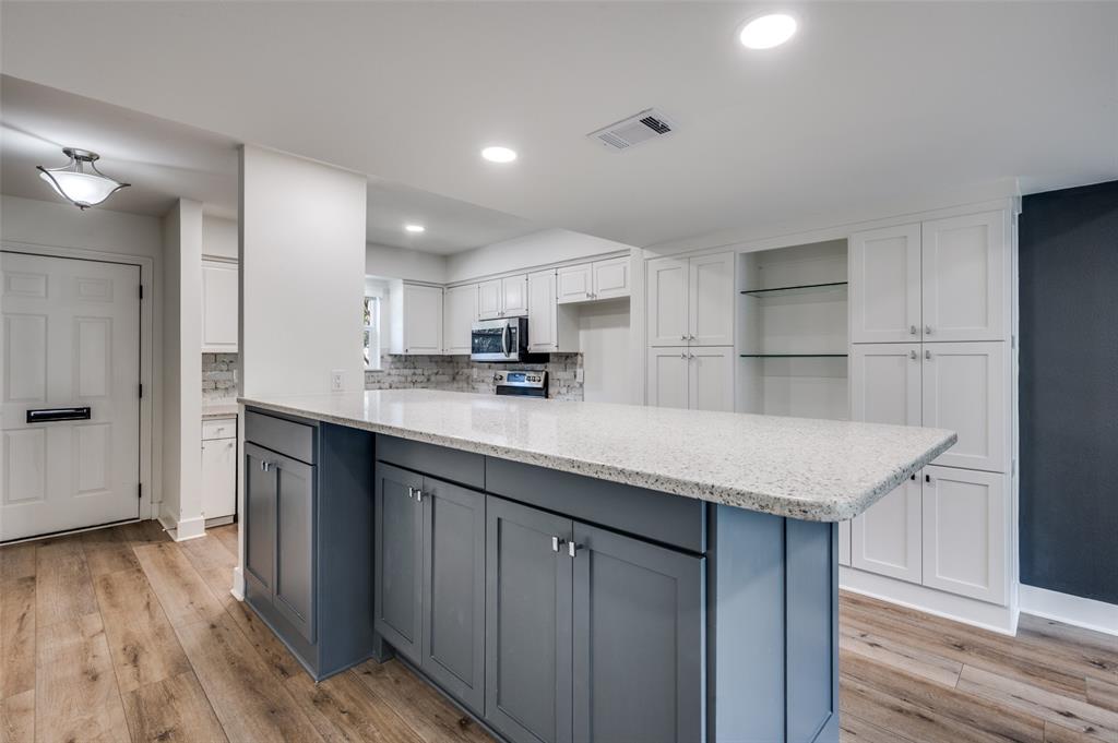1257 Roaring Springs Road Fort Worth, TX 76114 - Photo 5 of 11 a kitchen with kitchen island granite countertop wooden floors and white cabinets