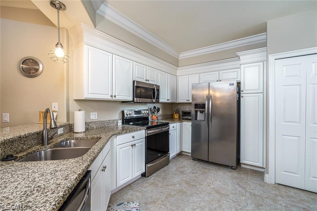 9667 Hemingway Lane, Unit 3107 Fort Myers, FL 33913 - Photo 8 of 23 a kitchen with granite countertop a sink a counter top space stainless steel appliances and cabinets