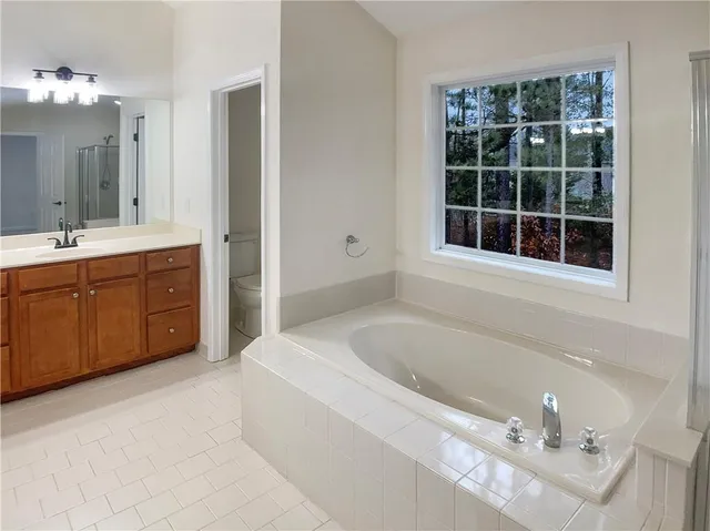 a spacious bathroom with a tub sink and mirror