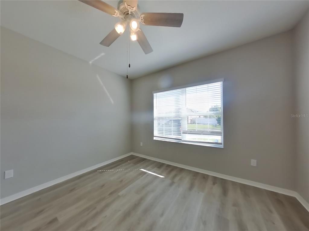 Undisclosed Address Zephyrhills, FL 33541 - Photo 17 of 21 an empty room with wooden floor chandelier fan and windows