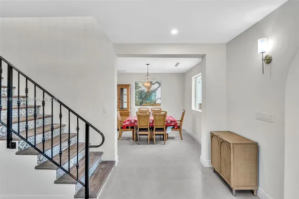 a kitchen with stainless steel appliances kitchen island granite countertop a dining table chairs refrigerator and sink