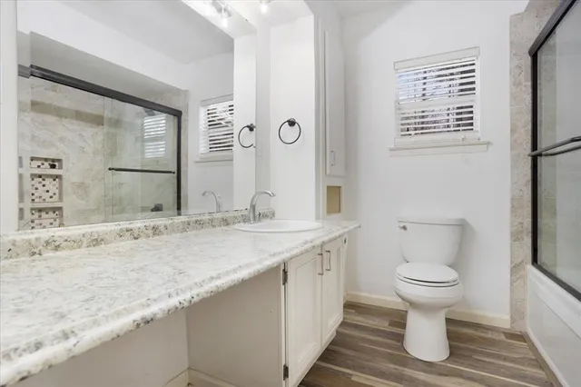 a bathroom with a granite countertop toilet sink and mirror