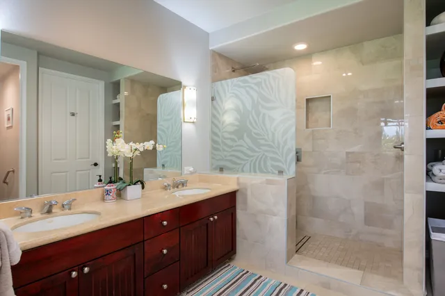 a bathroom with double vanity sinks and a shower