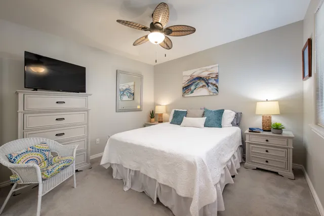 a bedroom with a bed a chandelier and a flat tv screen on dresser