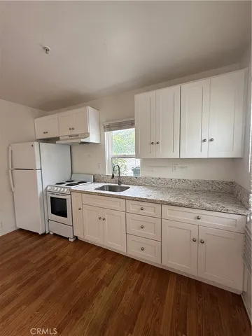 a kitchen with granite countertop white cabinets and white appliances