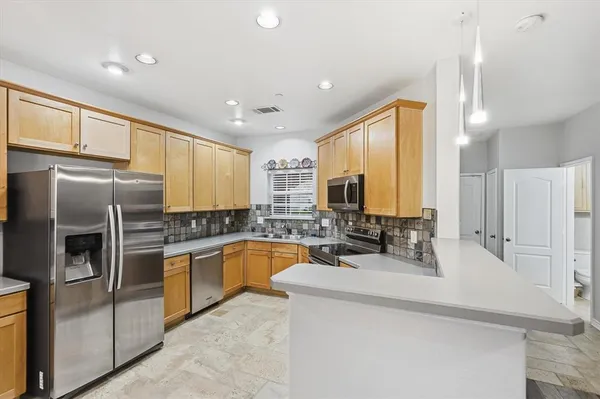 a kitchen with stainless steel appliances granite countertop a sink a stove a refrigerator a washer dryer and a refrigerator