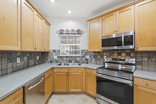 a kitchen with a sink a counter top space cabinets and stainless steel appliances