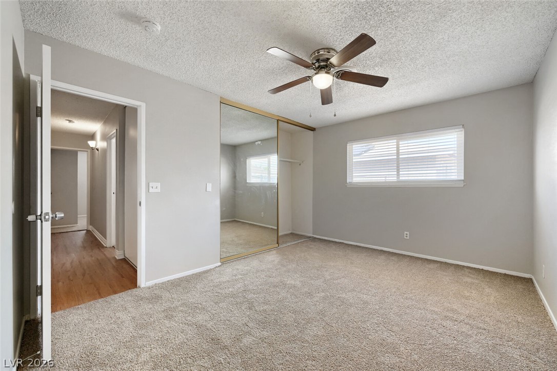 6321 Portola Road Las Vegas, NV 89108 - Photo 14 of 29 A well-lit bedroom features plush carpeting, a wide window for abundant light, and a spacious mirrored closet.