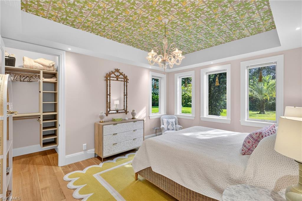 111 Caribbean Road Naples, FL 34108 - Photo 26 of 50 a spacious bedroom with a large bed and a chandelier