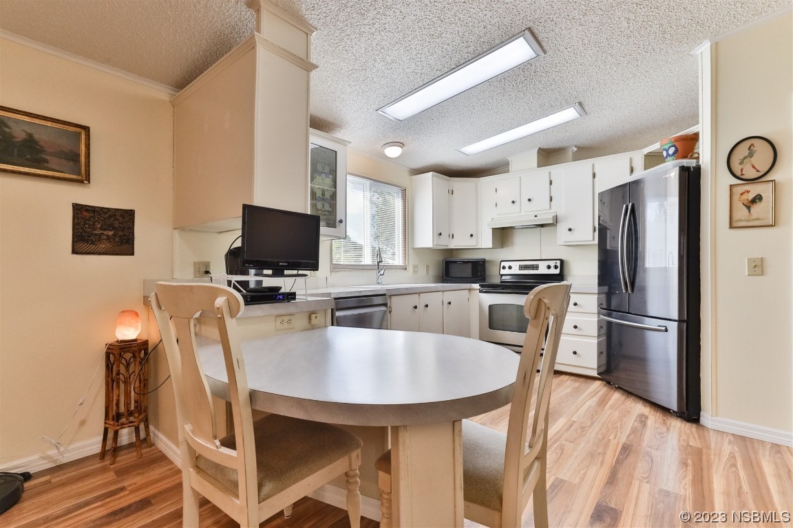 806 Navigators Way Edgewater, FL 32141 - Photo 20 of 59 a kitchen with stainless steel appliances a refrigerator a stove a microwave a dining table and chairs with wooden floor