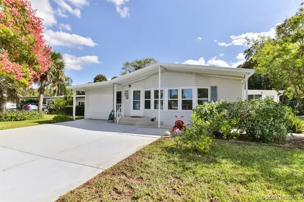 a front view of a house with a yard and potted plants