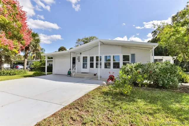 a front view of a house with a yard and potted plants