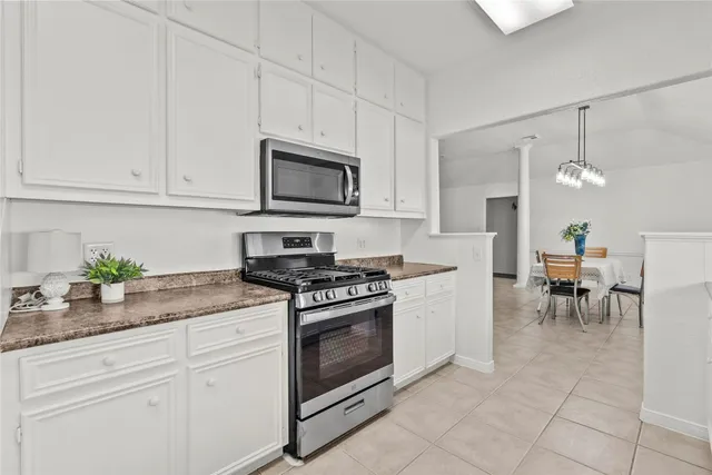 a kitchen with granite countertop white cabinets stainless steel appliances and a counter space