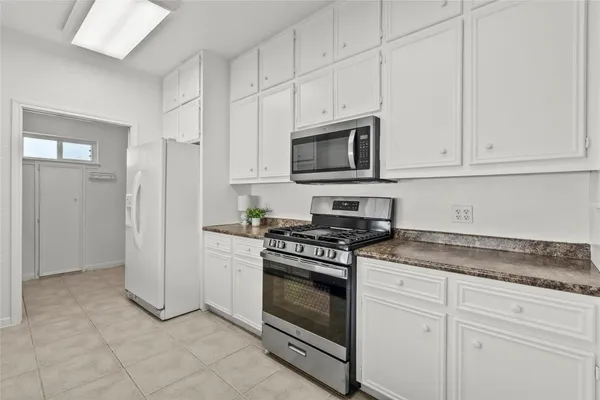 a kitchen with granite countertop white cabinets and stainless steel appliances