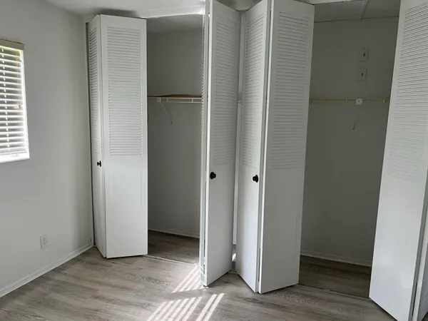 an empty room with wooden floor and closet
