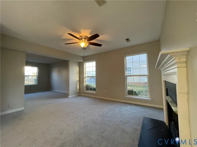 an empty room with windows and fireplace
