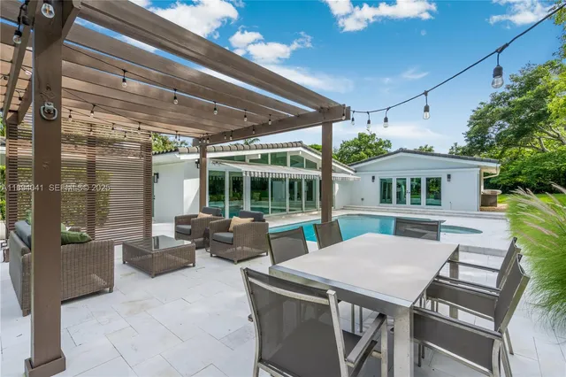 a view of pool with large windows and a yard with plants and large trees