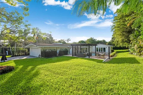 a view of a house with a yard deck and a large tree
