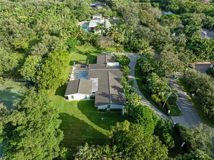 an aerial view of a house with a yard lake and outdoor seating