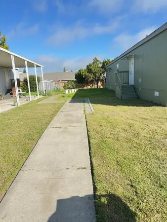 a view of a house with a big yard and large trees