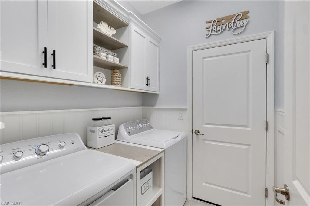 2187 Cara Cara Way Naples, FL 34120 - Photo 25 of 50 Laundry area with wainscoting, a decorative wall, washing machine and clothes dryer, and cabinet space