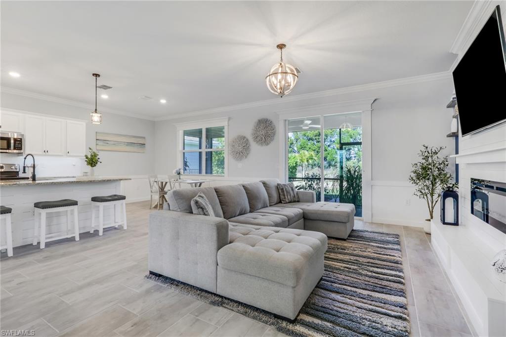2187 Cara Cara Way Naples, FL 34120 - Photo 9 of 50 Living room featuring crown molding, suspended lighting, and a glass covered fireplace
