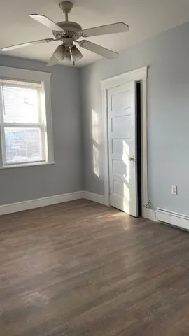 a view of an empty room with window and chandelier fan